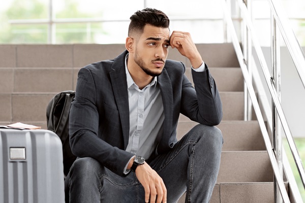cancellazione del volo. uomo arabo sconvolto seduto con i bagagli sulle scale dell'aeroporto