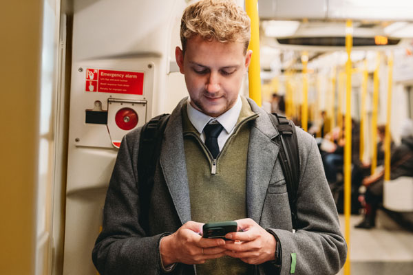 Man using smartphone on subway train.