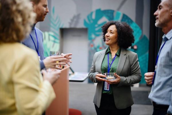 Dos hombres y dos mujeres discuten ideas en lo que parece ser una sala de juntas con paredes pintadas con diseños creativos.