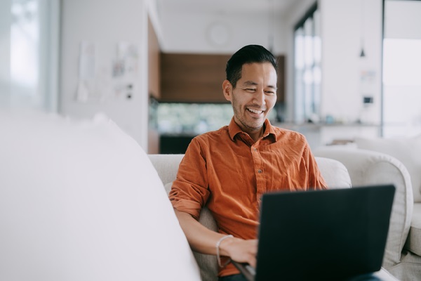 Smiling man using laptop at home