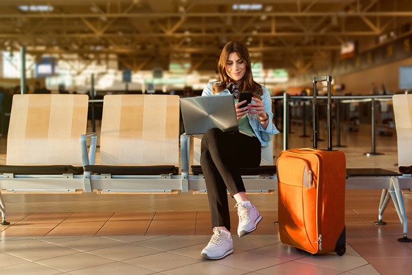 Traveler with laptop and suitcase at airport terminal.