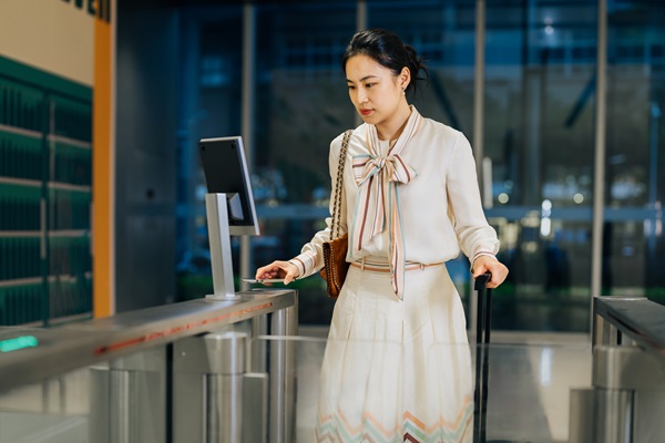 Woman with luggage using access control gate.