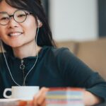 Femme souriante avec écouteurs devant un ordinateur portable.