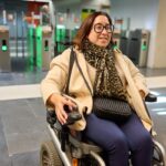 Woman in wheelchair at subway entrance smiling