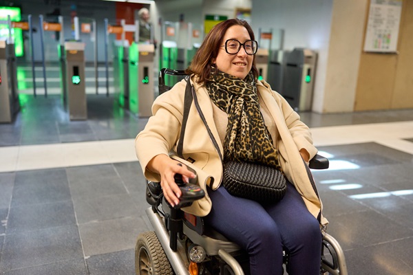 Woman in wheelchair at subway entrance smiling