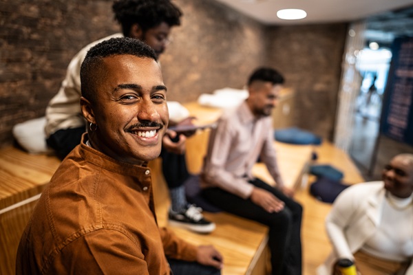 Lächelnde Person mit Freunden in lässiger Umgebung.