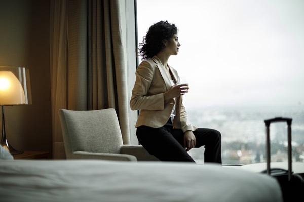 Person sitting by hotel window with city view.