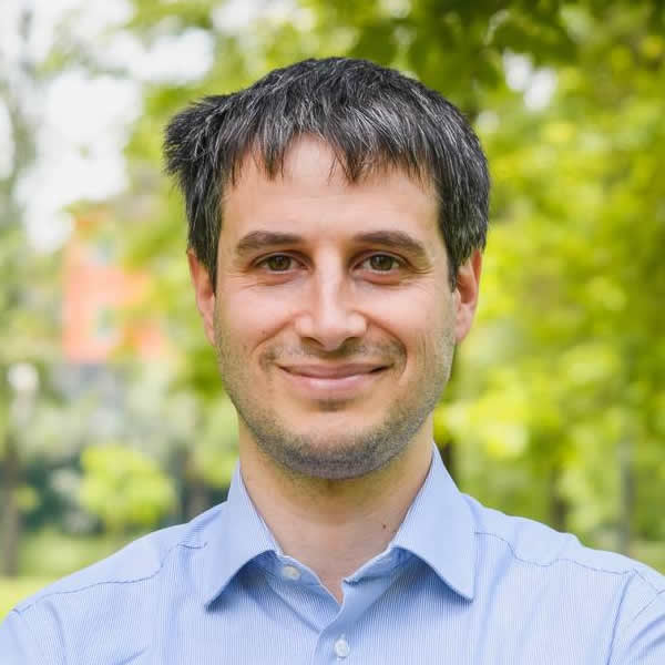 Mann lächelt im Park mit grünem Hintergrund