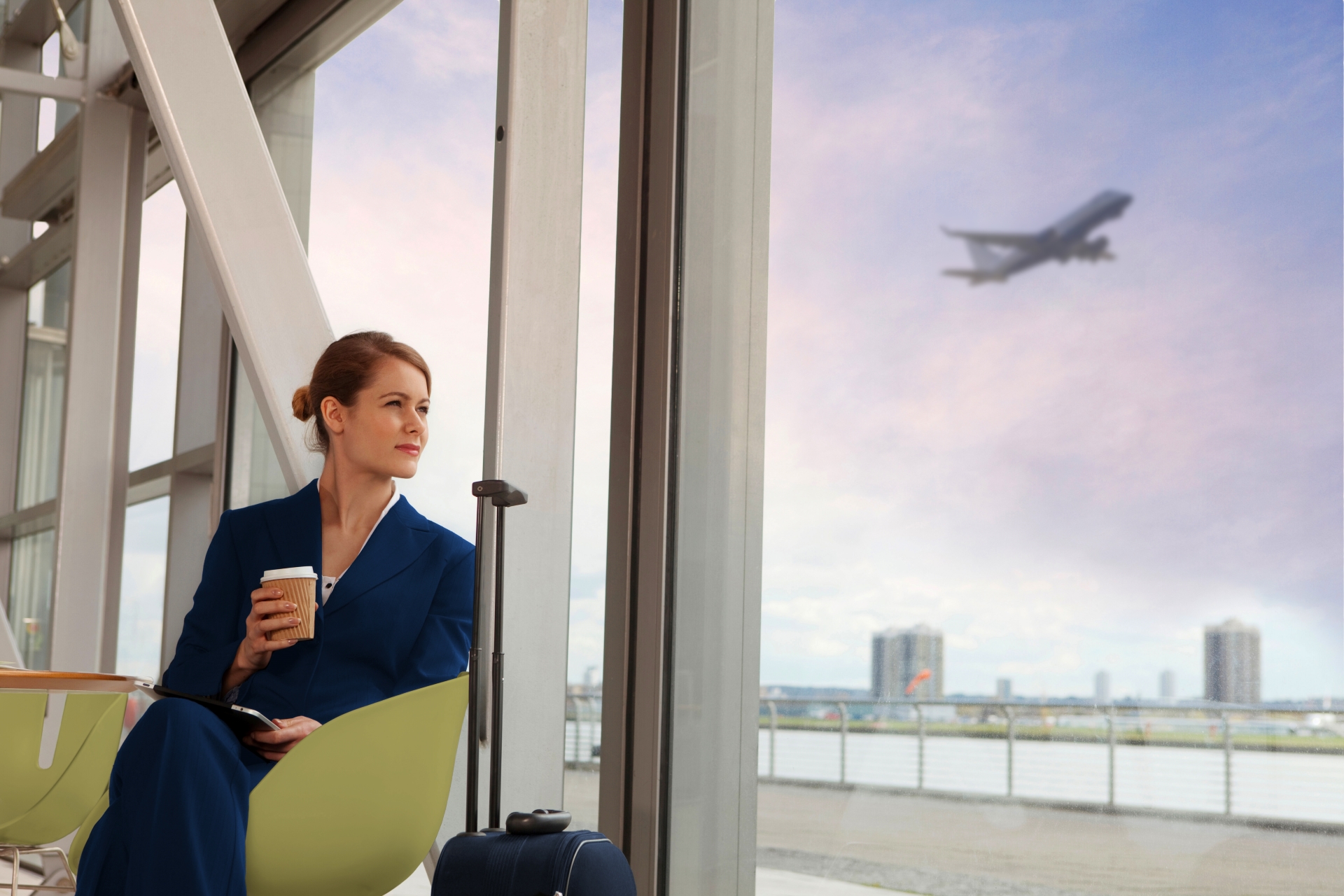 Woman in blue suit at airport holding coffee