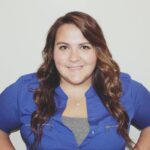 Smiling woman in blue shirt with long hair.