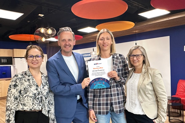 Four people holding a certificate in an office.