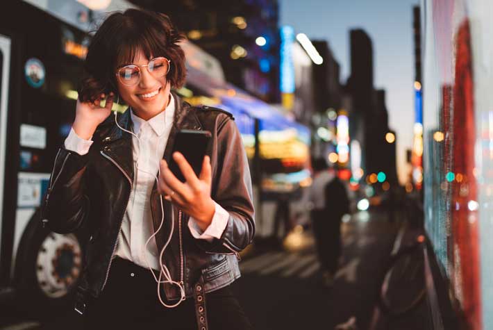 Woman smiling at phone on city street